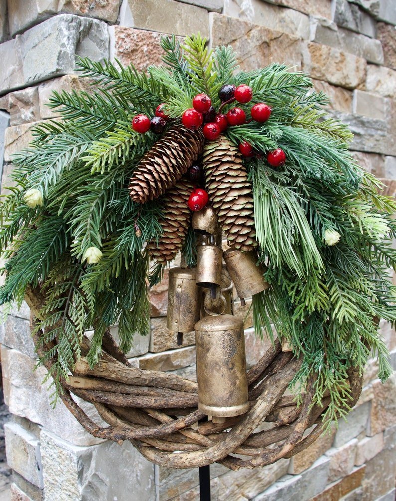 Corona de Navidad de estilo boho con base de ramas rústicas, piñas y campanas doradas