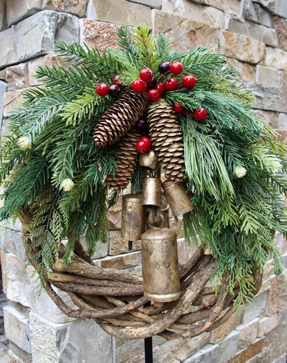Corona de Navidad de estilo boho con base de ramas rústicas, piñas y campanas doradas