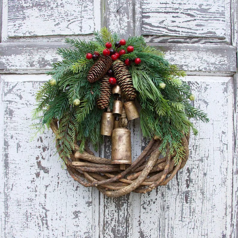 Corona de Navidad de estilo boho con base de ramas rústicas, piñas y campanas doradas